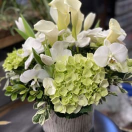 White calla lilies and green hydrangeas in a glass vase