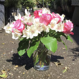 Pink roses and white alstroemeria in a clear glass vase