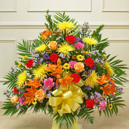 Large colorful floral arrangement with a yellow bow in a vase