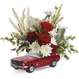 Red roses and white daisies arranged in a red toy car