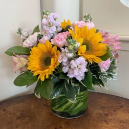 Sunflowers and pink flowers arranged in a glass vase