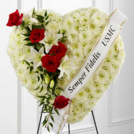 Heart-shaped funeral wreath with red roses and white flowers on a stand