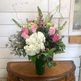 Pink roses and white hydrangea in a tall glass vase