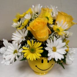 Yellow roses and white daisies in a smiley-face vase