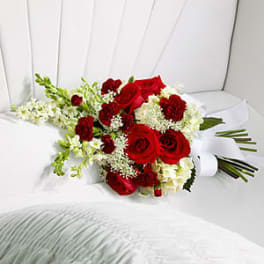 Red roses and white flowers arranged on a white chair