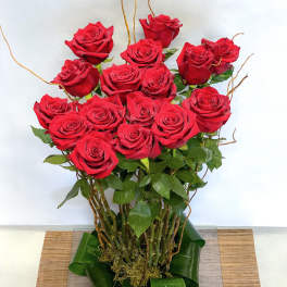 Tall bouquet of red roses with green leaves and decorative twigs