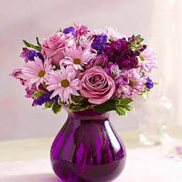 Pink and purple bouquet in a purple glass vase