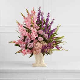 Pink and purple floral arrangement in a cream vase
