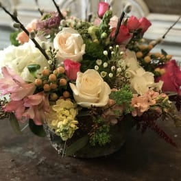 Mixed bouquet of roses, hydrangeas, and pink flowers in a low vase