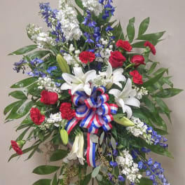 Standing floral spray with red roses, white lilies, and blue flowers