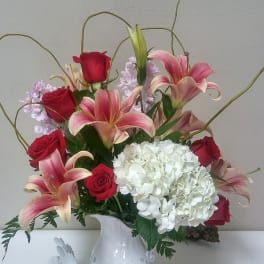 Bouquet of red roses, pink lilies, and white hydrangea in a white vase