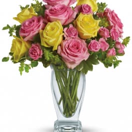 Pink and yellow roses arranged in a clear glass vase