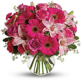 Pink roses, gerbera daisies, and lilies in a clear glass vase