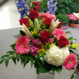 Mixed bouquet of red roses, pink gerberas, and white hydrangea in a glass vase