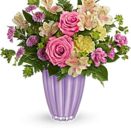 Pink roses and mixed flowers arranged in a purple vase