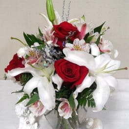 Red roses and white lilies in a clear glass vase with silver accents