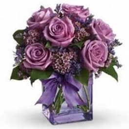 Purple rose bouquet in a square glass vase with a ribbon