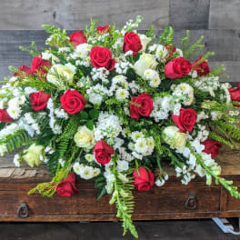 Large red and white rose and snapdragon spray arrangement on a wooden table
