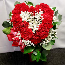 Heart-shaped bouquet of red carnations with white baby's breath and a red ribbon