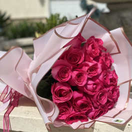 Bouquet of bright pink roses wrapped in pale pink paper