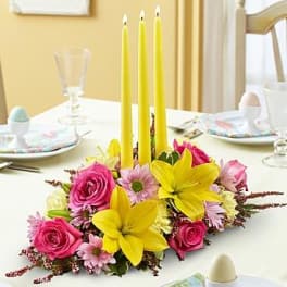 Floral table centerpiece with yellow candles and pink and yellow flowers