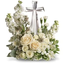 White floral wreath with roses and lilies around a silver cross