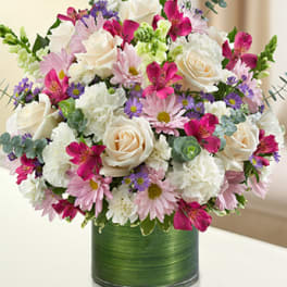 Mixed bouquet of white roses, pink daisies, and purple flowers in a green vase