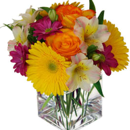 Bright mixed bouquet in a clear square vase