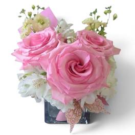 Pink roses and white flowers arranged in a square glass vase