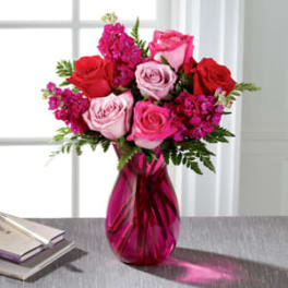 Pink and red roses in a magenta glass vase