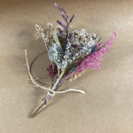 Small dried wildflower bouquet tied with twine on brown paper