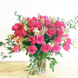 Pink roses arranged in a clear glass vase with small white filler flowers