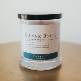 A scented candle in a clear glass jar with a black lid