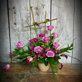 Pink roses and tulips arranged in a beige vase