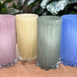 Four colored glass candle holders on a wooden surface