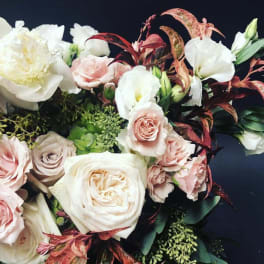Bouquet of pale pink and white roses with white blooms and dark foliage