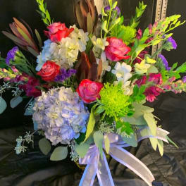 Colorful bouquet of roses, hydrangeas, and orchids with a ribbon bow