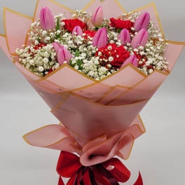Pink tulips and red carnations in a wrapped bouquet
