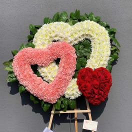 Heart-shaped floral wreaths in pink, white, and red on an easel