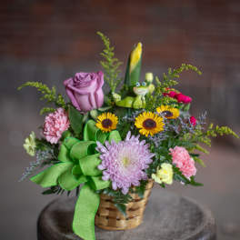 Basket arrangement with roses, chrysanthemums, carnations, and a small frog figurine