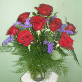 Bouquet of red roses with purple filler in a glass vase