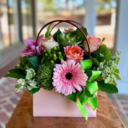 Pink and peach flower arrangement in a white gift box with a green ribbon