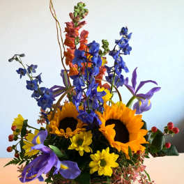 Basket arrangement with sunflowers, blue flowers, and purple irises