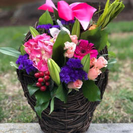 Pink and purple floral basket arrangement with roses and calla lilies