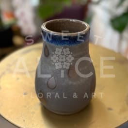 Small ceramic vase with a blue rim and teardrop cutouts