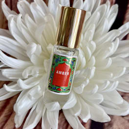 White flower with a small perfume bottle labeled Amber in the center