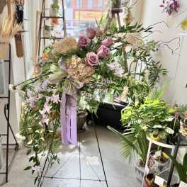 Lavender roses and pale hydrangeas in a cascading floral arrangement with ribbon