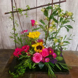 Mixed bouquet with pink roses, sunflowers, and magenta daisies in a low black base
