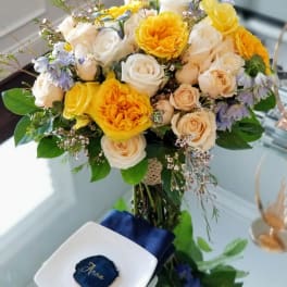 Bouquet of yellow, white, and peach roses with blue accents