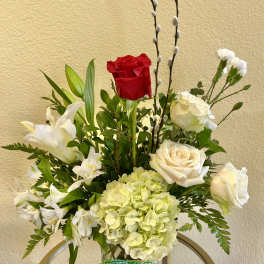Mixed bouquet with red and white roses, lilies, and pale hydrangea in a glass vase